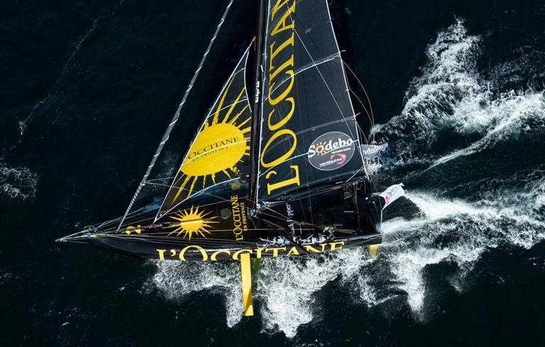 Voilier IMOCA L’Occitane en Provence vu du ciel en navigation lors de la Route du Rhum 2026 – Destination Guadeloupe, monocoque à foils sur l’océan Atlantique.