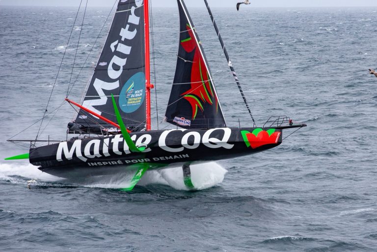 Voilier IMOCA Maître Coq en course lors de la Route du Rhum 2026 – Destination Guadeloupe, monocoque de course naviguant à grande vitesse sur l’océan Atlantique.