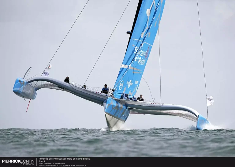 Trimaran Ocean Fifty en pleine navigation lors de la Route du Rhum 2026 – Destination Guadeloupe, bateau de course survolant légèrement l’eau grâce à sa vitesse.