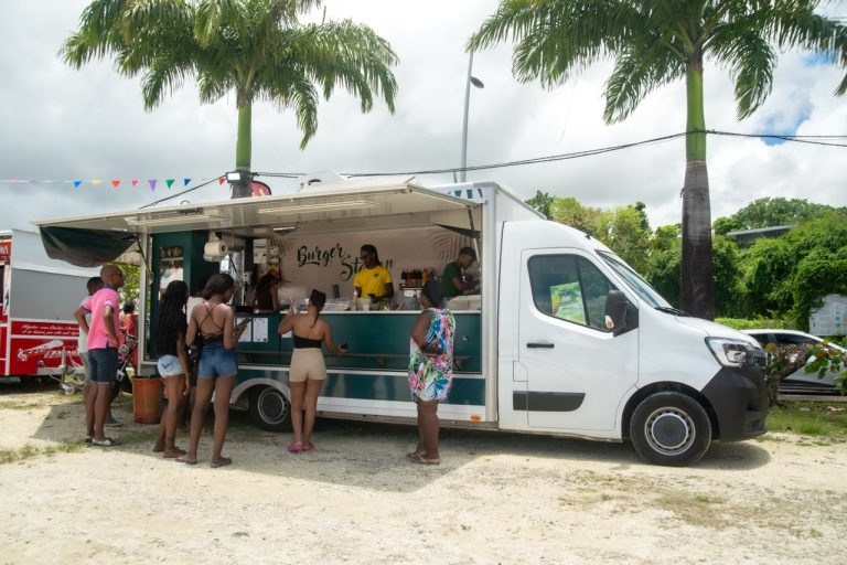 Food truck de burgers lors de La Foire des Roulottes à Pointe-à-Pitre en Guadeloupe avec visiteurs faisant la queue pour découvrir les spécialités de restauration rapide.