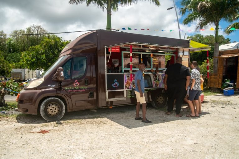 Food truck de restauration installé lors de La Foire des Roulottes à Pointe-à-Pitre en Guadeloupe avec visiteurs venus découvrir les spécialités culinaires proposées pendant l’événement.