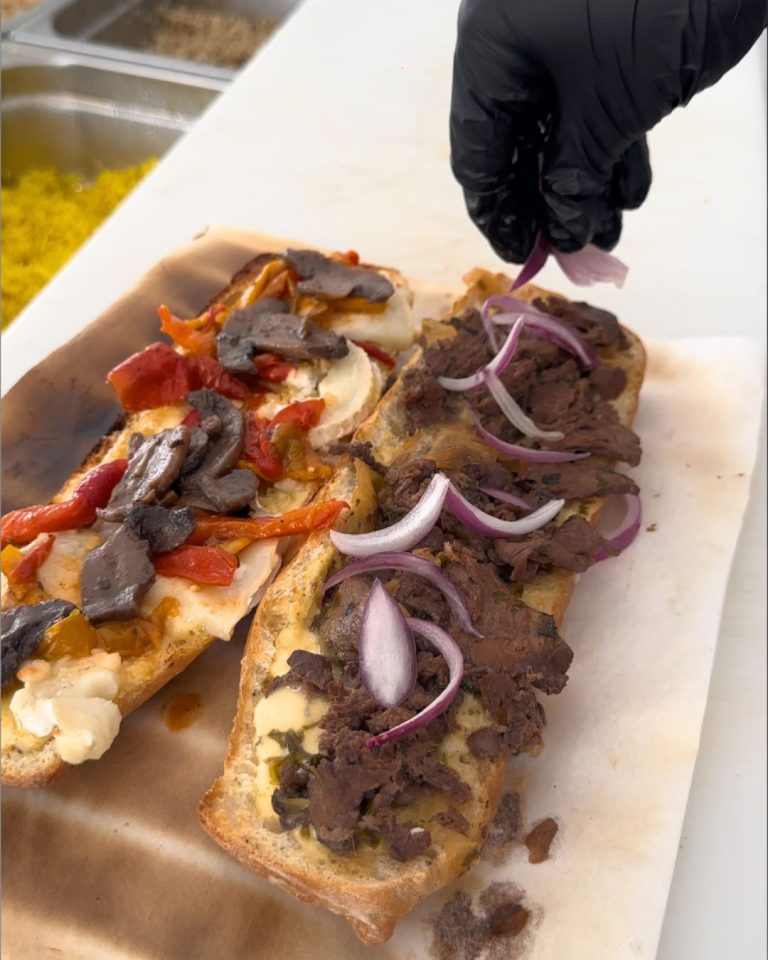 Préparation de sandwichs artisanaux au snack Bun Me au Gosier en Guadeloupe avec viande marinée, légumes grillés, fromage et ingrédients frais.