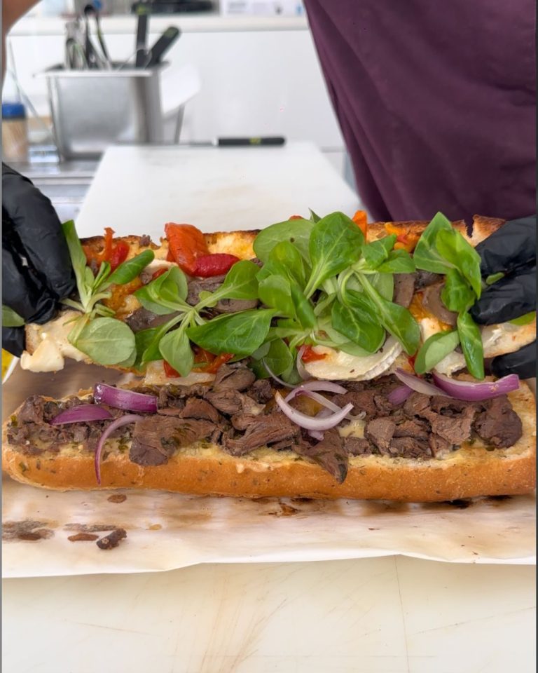 Grand sandwich gourmand préparé au snack Bun Me au Gosier en Guadeloupe avec viande marinée, légumes grillés, salade fraîche et ingrédients généreux.