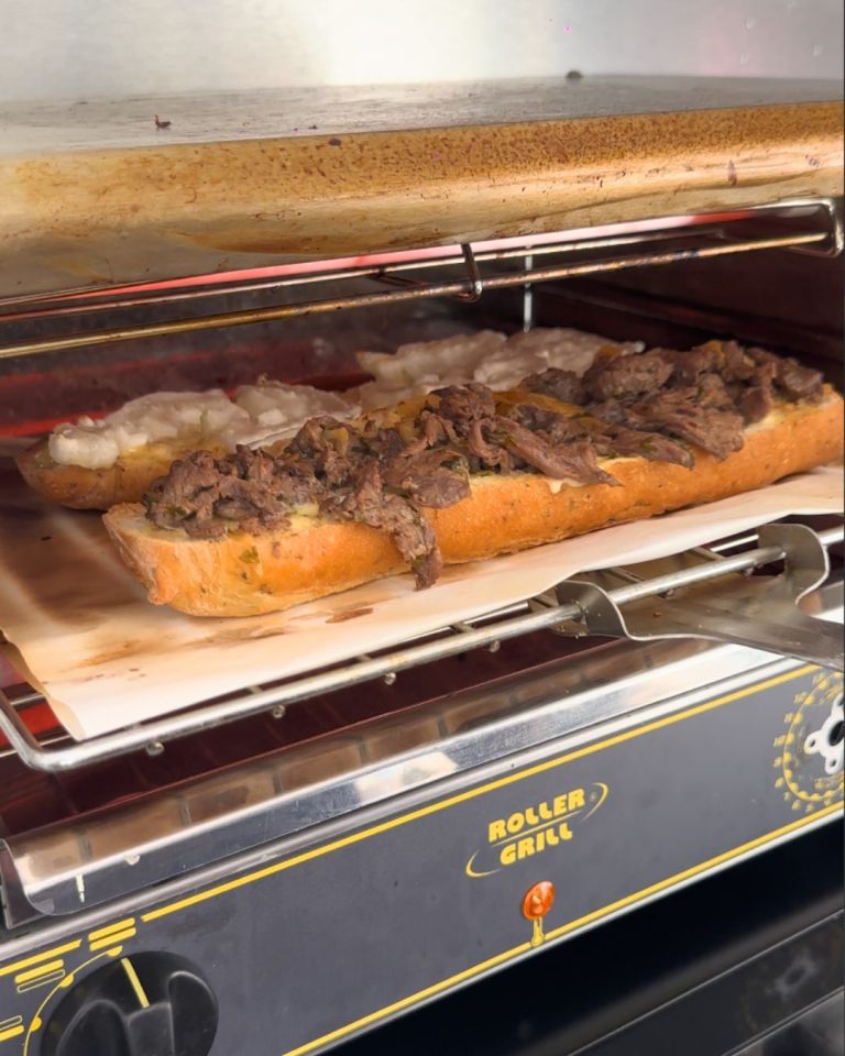 Sandwich gratiné préparé au snack Bun Me au Gosier en Guadeloupe avec viande, fromage fondu et ingrédients généreux dans un four grill professionnel.